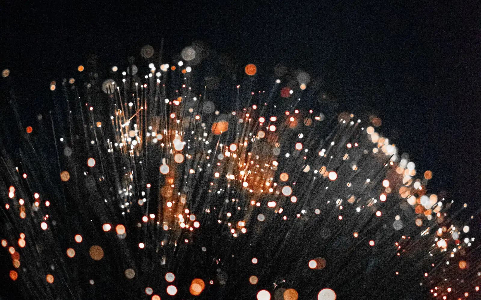 Orange fibre optics on black, standing in for systems in sync